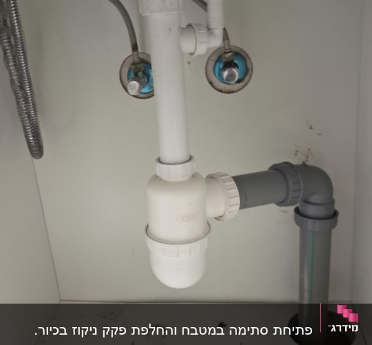 צנרת מתחת לכיור עם ברזים וצינורות